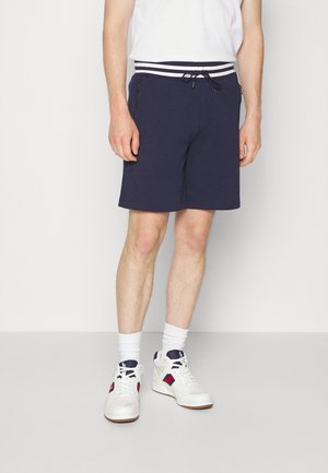 Navy blue shorts in a soft fabric with a striped waistband and drawstring. Features zippered side pockets and a relaxed fit.
