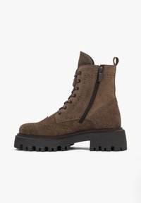 Brown suede ankle boot with a chunky rubber sole, round toe, side zipper, and decorative brogue detailing on the upper.