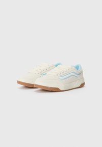 Cream canvas sneakers with light blue accents. Features include a textured sole, perforated detailing, and traditional lace-up closure.