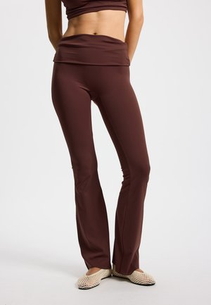 Braune ausgestellte Yogahosen mit einem breiten Bund, aus dehnbarem Stoff. Verfügen über eine glatte, elegante Textur und eine maßgeschneiderte Passform.