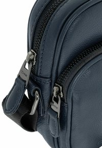 Granatowa skórzana torba z podwójnymi zamkami błyskawicznymi, teksturowaną powierzchnią i metalowymi detalami. Posiada gładkie linie i praktyczne elementy designu.