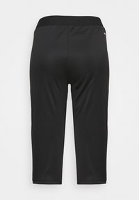 Černé sportovní legíny až ke kotníkům se širokým pasem, zobrazené zezadu na čistém bílém pozadí.