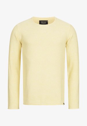 Suéter de punto amarillo de manga larga con escote redondo, tejido texturizado y una pequeña etiqueta con el logo en el dobladillo. Ajuste recto, sin patrones.