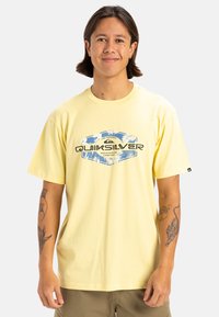 Camiseta de algodón amarilla con corte relajado, que presenta un estampado gráfico multicolor y un logo en el frente. Mangas cortas, escote redondo.