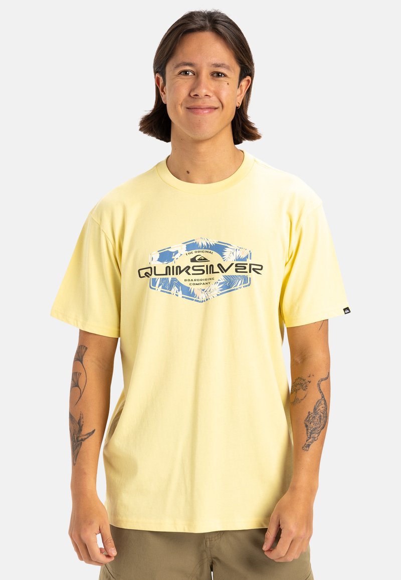 Camiseta de algodón amarilla con corte relajado, que presenta un estampado gráfico multicolor y un logo en el frente. Mangas cortas, escote redondo.