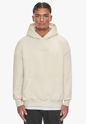 Cremefarvet hoodie med en frontlomme, oversized pasform og ribbede manchetter. Har et diskret broderet logo på brystet.