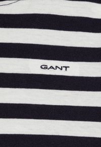 Marineblå og hvite stripete bomulls t-skjorte med en liten svart "GANT" logo, med en glatt tekstur og klassisk crew neck design.