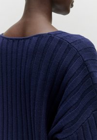 Dunkelblaues geripptes Oberteil mit weitem Ausschnitt und strukturierter Stoffqualität. Das Design zeichnet sich durch ausgeprägte vertikale Streifen auf der Rückseite aus.