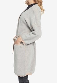 Grijze gebreide cardigan met lange mouwen, wikkelontwerp, zakken en een contrasterende beige strikceintuur. Geweven stof met een scalloped zoomdetail.
