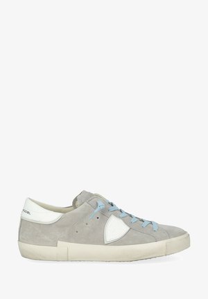 Baskets en daim gris avec des accents blancs, des lacets bleu clair, un bout arrondi et une semelle en caoutchouc texturée. Présentent un emblème reconnaissable sur le côté.