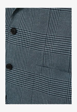 Tumši zilas krāsas audums ar rakstu, kas sastāv no pārbaudītu kvadrātu, ar kontrastējošām gaišākām kvadrātveida formām un melnām pogām. Visā audumā ir smalkas izstrādājuma detaļas.