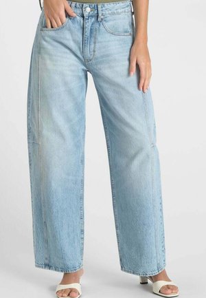 Lichtblauwe denim wijde broek met zichtbare stiksels, voorzakken en een taillehoog design, gecombineerd met witte sandalen met bandjes.