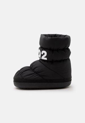 Chausson-botte noir matelassé avec semelle épaisse et inscription blanche "Q2" sur le revers supérieur, montré de profil sur fond blanc.