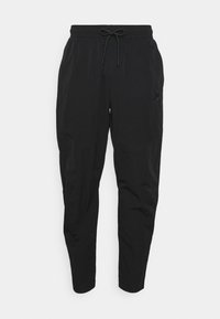 Pantalones negros ajustados hechos de tejido ligero, con una cintura elástica con cordón, bolsillos laterales y textura suave.