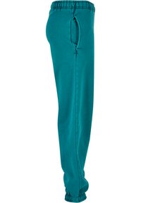 Teal joggebukser med elastisk linning, sidelomme og elastiske mansjetter ved anklene. Laget av myk, pustende stoff.