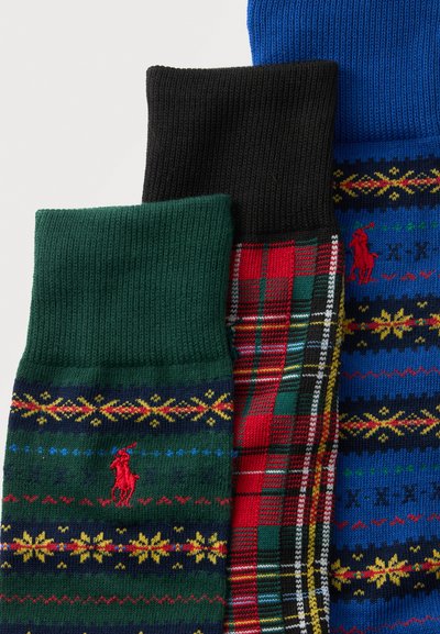 Trois chaussettes pliées en vert, noir et bleu ; les vertes et bleues ont des bandes à motifs jaunes et rouges ainsi que des logos rouges de joueur de polo, la noire a un motif à carreaux rouges.