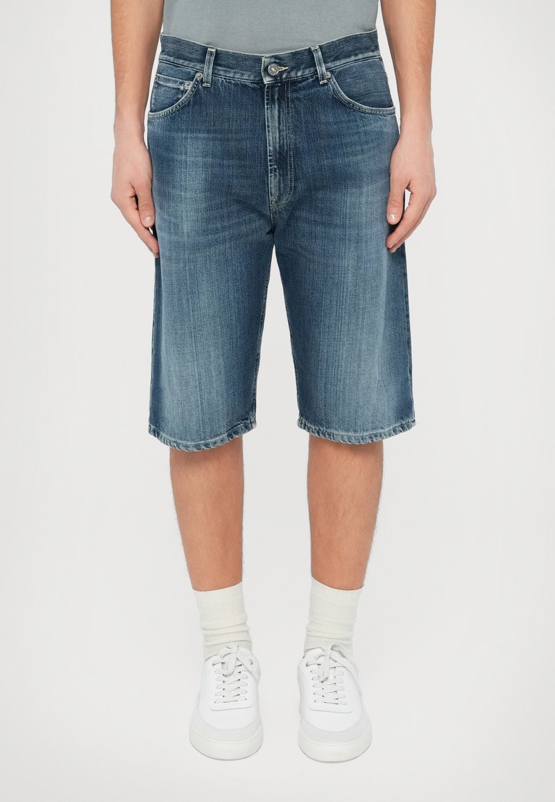 Σορτς τζιν μπέρμποντα σε μεσαίο μπλε χρώμα, με πέντε τσέπες, φερμουάρ και διακριτική ξεθώριαση. Το τελείωμα είναι ραμμένο για ανθεκτικότητα. Φοριέται με λευκά αθλητικά παπούτσια.