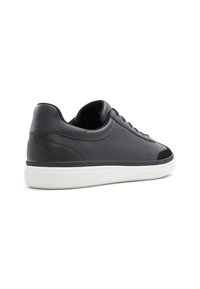 Zapatillas de cuero negro con una textura suave, suela de goma blanca, forma redondeada y diseño minimalista. Presentan cordones y un collar acolchado.