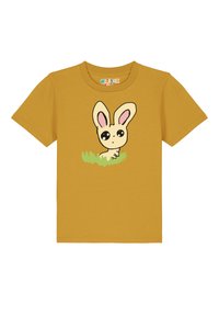 Geel katoenen t-shirt met een cartoon konijn ontwerp met grote ogen en roze oren, geplaatst in groen gras. Korte mouwen en ronde hals.
