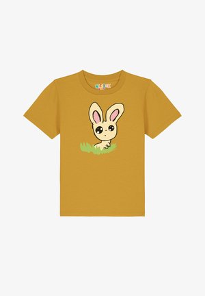 T-shirt en coton jaune avec un design de lapin animé aux grands yeux et oreilles roses, positionné dans de l'herbe verte. Manches courtes et col rond.