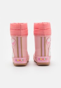 Stivali da pioggia in gomma rosa con finitura testurizzata, polsini foderati in pile, che presentano icone giocose e un branding colorato sul tallone.