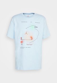 T-shirt en coton bleu clair avec des graphiques, y compris un logo Jumpman, du texte et des éléments numérotés dans des couleurs contrastées. Manches courtes, col rond.