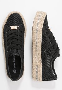 Sneaker nere in rete con suola in juta intrecciata, dotate di un accento metallico e lacci neri. La suola presenta un dettaglio a striscia argentata.