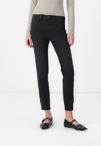 Svarta jeans med slim fit, fem fickor och något avskuren ankeldel med dragkedjedetalj. Matchas med svarta platta skor prydda med öglor.