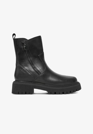 Bota de cuero negro hasta el tobillo con suela gruesa acanalada, cremallera lateral, lengüeta para tirar y puntera redonda, mostrada de perfil sobre fondo blanco.