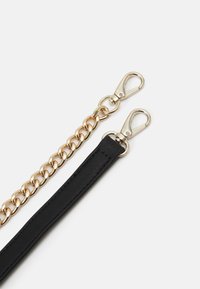 Musta kangas hihna, joka on kiinnitetty kultaketjuun, ja siinä on kullasta valmistetut klipsilukot kummassakin päässä. Ketjussa on sileitä, pyöristettyjä lenkkejä.