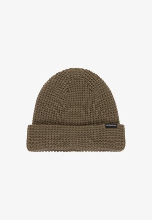 Gorro de punto marrón con un puño doblado y un patrón texturizado. Presenta una etiqueta de marca en el lateral. Probablemente de material de algodón o lana.