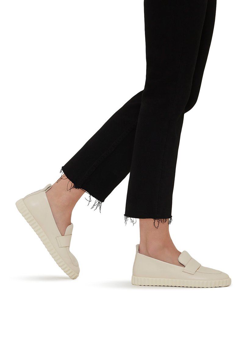 Beige slip-on shoes with a smooth leather finish, featuring a wide strap across the front and a textured rubber sole.