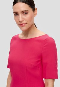 Robe fuchsia midi avec des manches courtes et un col large. Tissu lisse avec une texture subtile, dotée d'une poche sur la coutume latérale.