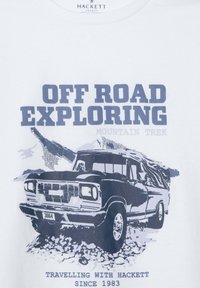 Camiseta blanca con estampado gráfico de un camioneta todoterreno en color azul marino. El texto dice "EXPLORACIÓN OFF ROAD", con elementos de montañas y naturaleza en el fondo.