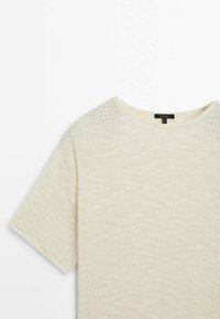 Kortærmet crew-neck top lavet af tekstureret, lys beige stof. Den har en afslappet pasform og et simpelt design uden synlige mønstre eller accenter.