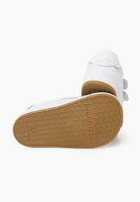 Sneakers bianchi per bambini con due cinturini in Velcro, suola in gomma testurizzata e suola esterna marrone con motivo a losanghe. Marchio visibile di lato.