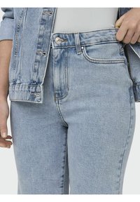 Jean en denim bleu clair avec taille haute et jambe droite, dotés de poches avant, d'une fermeture à un bouton et d'un léger délavage.