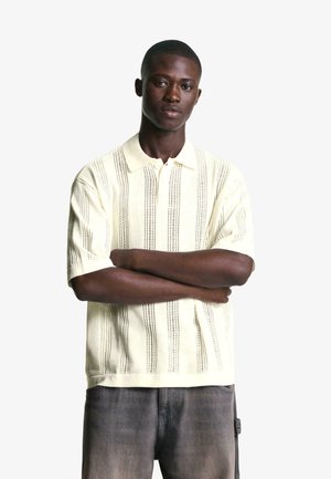 Gehaakt poloshirt in lichtgeel met een verticale streepjespatroon en korte mouwen; beschikt over een kraag en een sluiting met drie knopen.