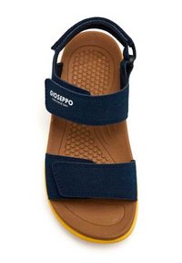 Sandalia de color azul marino con dos correas ajustables de Velcro, suela de goma texturizada y plantilla marrón con patrones circulares. Logo de la marca en la correa.