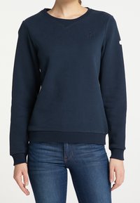 Sudadera de color azul marino hecha de algodón con un cuello, puños y dobladillo acanalados. Presenta un logo de ancla bordado en el pecho.