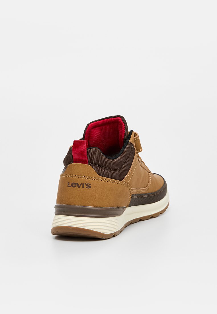 Zapatilla de cuero marrón con detalles en malla roja y marrón. Con un collar acolchado, entresuela blanca y suela de goma texturizada. Logo de Levi's presente.