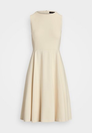 Une robe sans manches en tissu blanc cassé avec un col rond et une fermeture éclair dissimulée à l'arrière, présentant un design lisse et épuré.