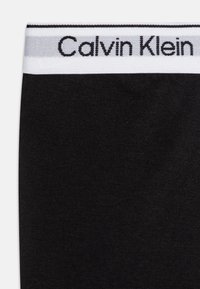 Čierny pás z bavlny s prímesou s logom "Calvin Klein" v bielej farbe, hladkou textúrou a jemným leskom. Zosilnené švy na okrajoch.