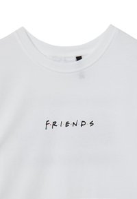 T-shirt bianca in cotone con design a collo rotondo. La parte frontale presenta "F.R.I.E.N.D.S" in testo nero con puntini colorati tra le lettere.