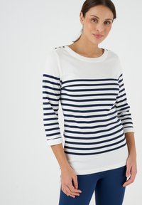 Weiß und marineblau gestreiftes Langarmshirt mit Rundhalsausschnitt und dekorativen goldenen Knöpfen an der Schulter. Aus weichem Baumwollmischmaterial.