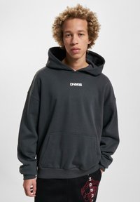 Dark gray hoodie with a front pocket and ribbed cuffs, featuring a white logo on the chest. Smooth texture, casual design, oversized fit.