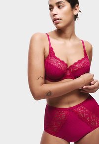 Ensemble soutien-gorge fuchsia et culotte taille haute avec accents en dentelle et motif à pois. Le matériau semble lisse avec des détails complexes sur les bords.