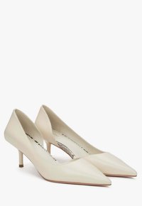 Krémové kožené lodičky s špičatou špičkou, nízkým podpatkem a vykrojením vzadu, s hladkým povrchem a minimalistickým designem.
