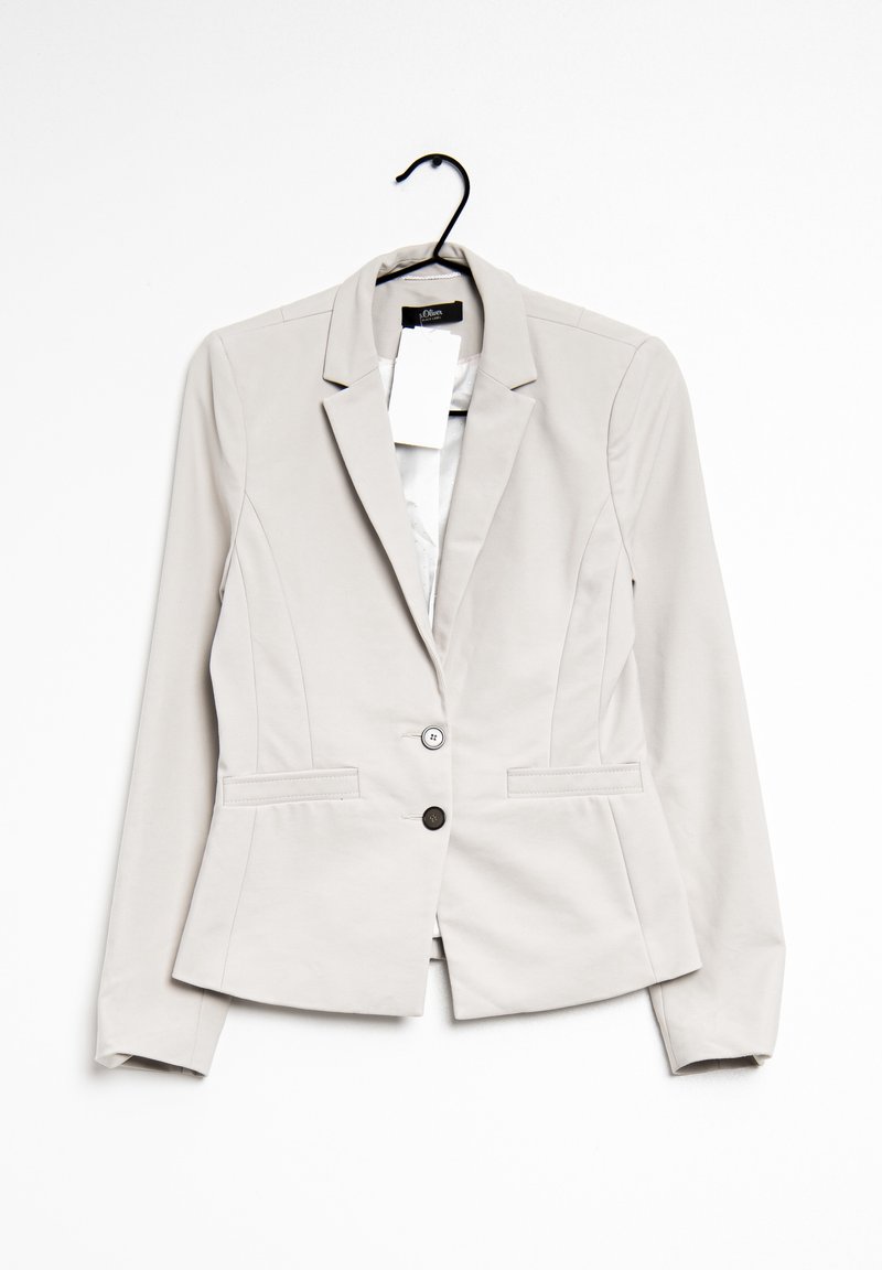 Blazer beige clair pour femme avec deux boutons, revers crantés et poches avant, suspendu à un cintre noir avec étiquette de marque visible et étiquettes de prix.