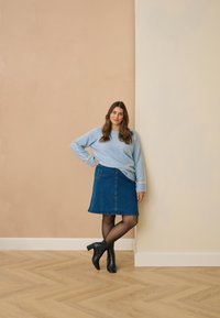 Pull bleu clair, jupe en denim coupe trapèze, collants noirs et bottines. Texture lisse, design décontracté, avec des rayures horizontales sur les manches.